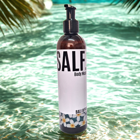 A bottle of SALF. Bali Affair Body wash standing in a tropical scene of palm trees and tropical waters