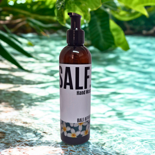 Bottle of 'SALF' hand wash with a floral label on a reflective water surface.