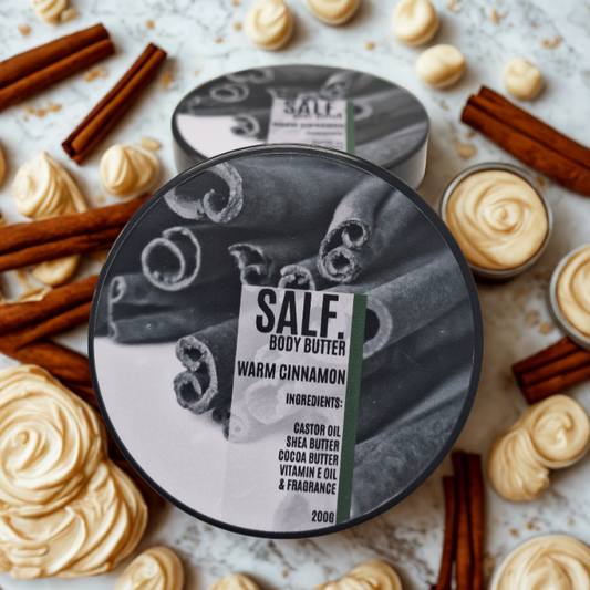 Body butter container labeled 'SALF. Body Butter Warm Cinnamon' surrounded by cinnamon sticks and cream on a light background.